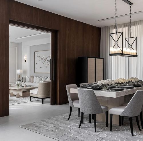 Dining room with stone table, grey upholstered chairs, candle chandelier, and view through sliding wood door to living room