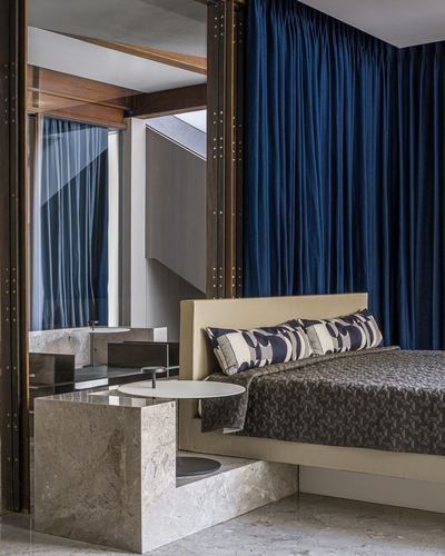 Bedroom with navy velvet drapery, stone platform base, and mirrored wood-framed partition