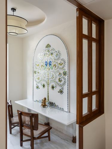 Arched decorative mural above marble console with brass idol, seen through wooden framed door