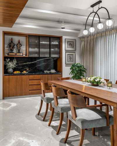 Wooden dining table with cane-back chairs beside a marble-backed sideboard and glass cabinet