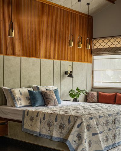 Bedroom with fluted wood wall, brass pendant cluster, and block-print quilt bedding