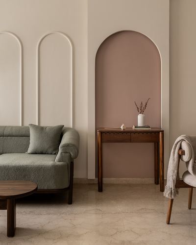 Living room corner with sage boucle sofa, arched niche wall, and wooden console table