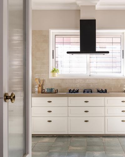White shaker cabinetry kitchen with beige tiled backsplash and black chimney hood over cooktop