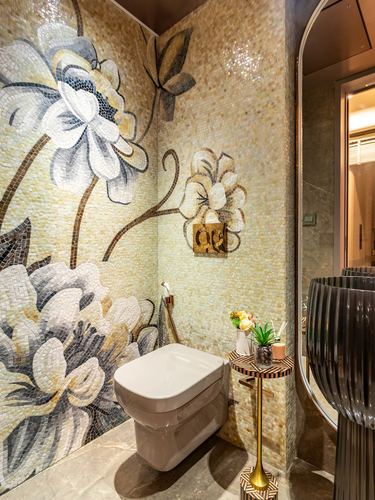 Powder room with floral mosaic tile walls, wall-hung toilet, and small round side table