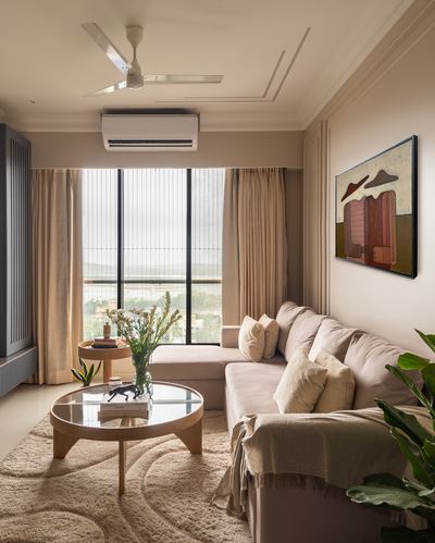 Beige living room with sectional sofa, round wood coffee table, and city view window