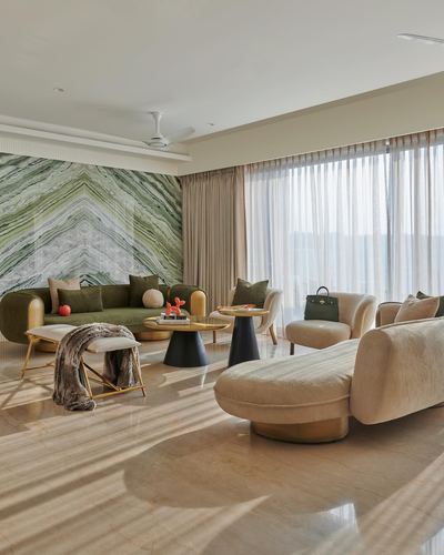 Living room with chevron marble feature wall, curved olive sofa and cream chaise on marble floor