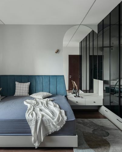 Bedroom with teal channel-tufted headboard, arched mirror niche, and fluted glass wardrobe