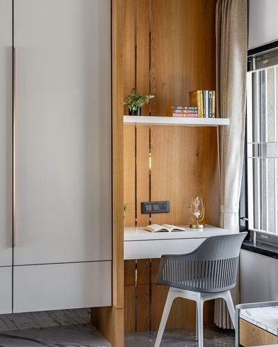 Built-in study nook with wood panelling, floating shelf with books, desk and grey chair