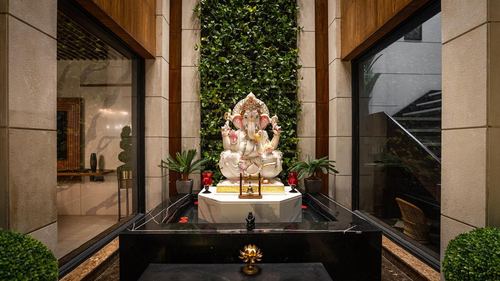 Marble Ganesh idol in a niche framed by a green living wall at a home entrance