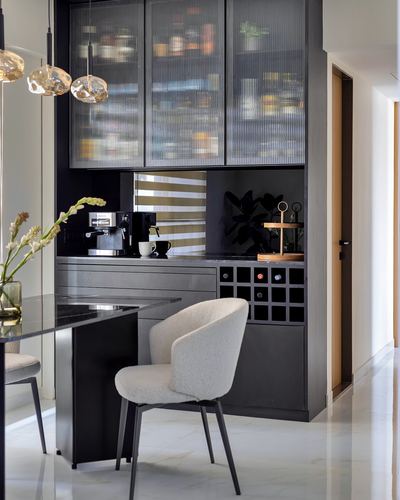 Dark fluted-glass cabinetry with wine rack and boucle chair in a modern kitchen bar nook