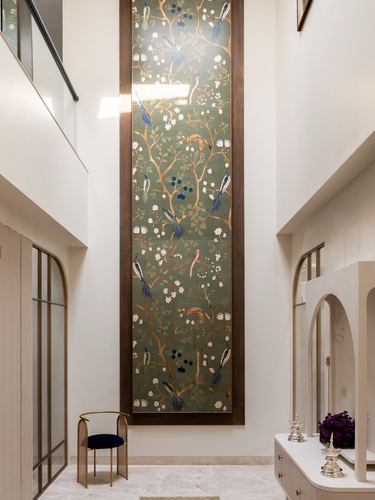 Double-height foyer with tall framed botanical wallpaper panel and arched doorways