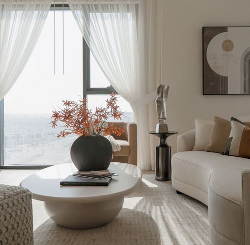 Living room with round pedestal table, sculpture, and curved sofa facing city-view window