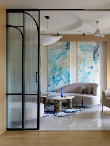 Living room with arched reeded glass door, curved beige sofa, and blue abstract artwork panels