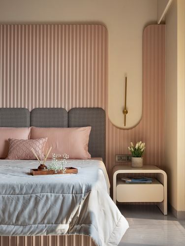 Bedroom with fluted pink panelling, houndstooth headboard, and curved wall niche with brass sconce