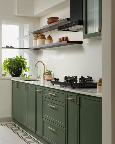 Green shaker cabinetry kitchen with brass handles, open stone shelves and black chimney hood