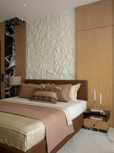 Bedroom with leather headboard, textured stone wall panel, wood wardrobes and marble-clad nightstand