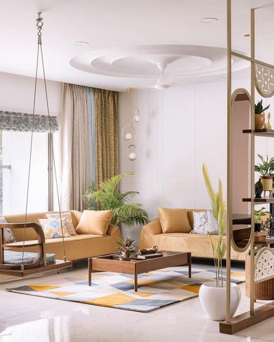 Living room with mustard sofas, wooden swing, and geometric rug under circular ceiling detail