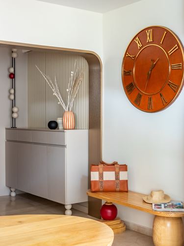 Foyer with fluted arched cabinet, oversized orange wall clock, and wooden bench