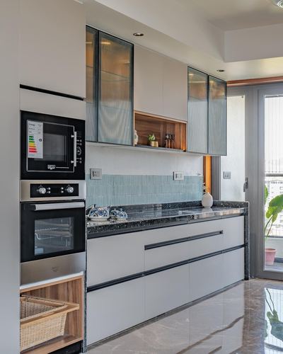 Modern kitchen with stone countertop, reeded glass cabinets, built-in ovens and mint tile backsplash