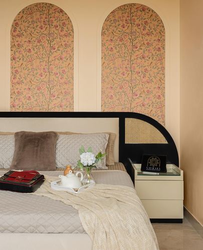 Bedroom with cane headboard, floral arched wallpaper panels, and breakfast tray on bed