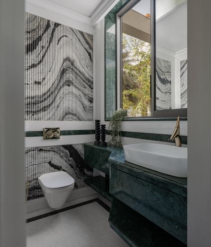 Bathroom with fluted marbled wall, green stone vanity, wall-hung toilet, and window framing greenery