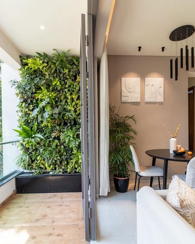 Balcony with vertical garden wall opening into a dining area with cluster pendant lights