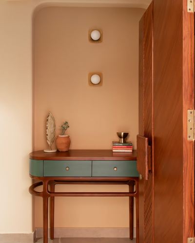 Console table with sage-green drawers set in a terracotta arched niche beside a wooden door