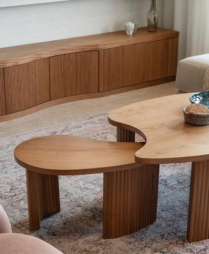 Organic-shaped wooden coffee table with ribbed legs beside a fluted wood console in a living room
