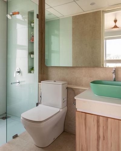 Bathroom with green vessel sink, wood vanity, glass shower, and sage tiled niche