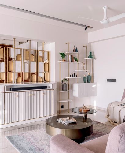 Living room with brass ladder shelving, fluted cabinetry, and round brass coffee table