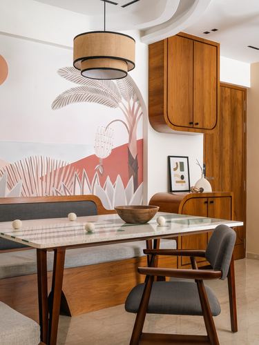 Dining nook with terrazzo table, curved wood cabinets, and a tropical mural wall