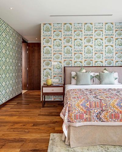 Bedroom with green botanical wallpaper, wood floor, and patterned bedspread