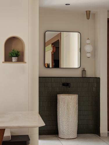 Bathroom vignette with fluted dark tile, sculptural basin, square mirror and globe pendant light