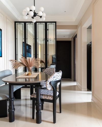 Dining area with black oval table, floral chairs, and mirrored partition screen in neutral hallway