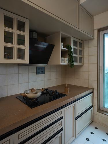Mumbai kitchen corner with cream cabinetry, black chimney hood, and stone countertop with hob