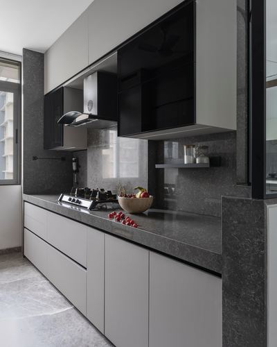 Grey stone kitchen with black upper cabinets, chimney hood, and gas cooktop with fruit bowl