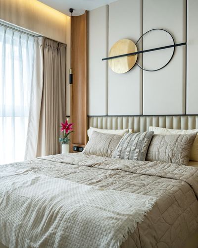 Beige bedroom with channel-tufted headboard, sheer curtains, and circular wall art above bed