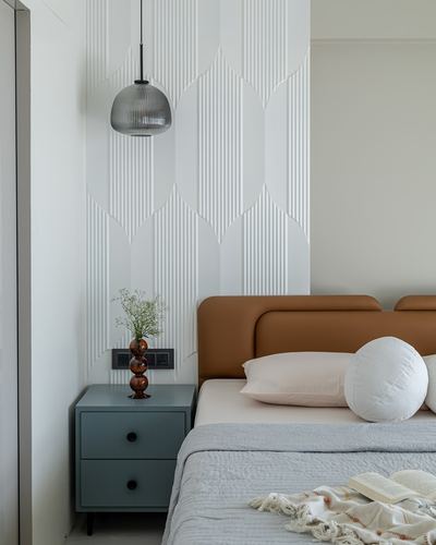 Bedroom corner with textured white wall panel, ribbed pendant light, and tan leather headboard