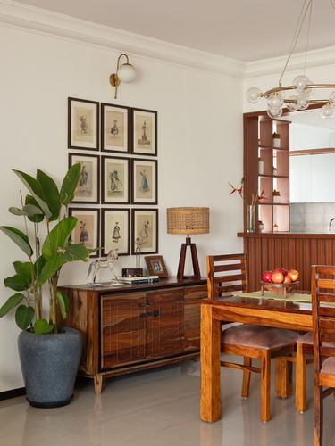 Dining area with wooden sideboard, gallery wall, rattan lamp, and dining table with fruit bowl