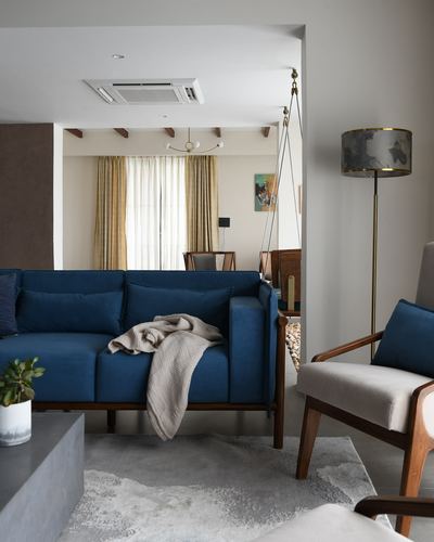 Blue velvet sofa and cane armchair in living room with jhula swing visible through arched opening