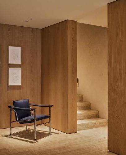 Wood-panelled foyer with black leather armchair beside a stone staircase