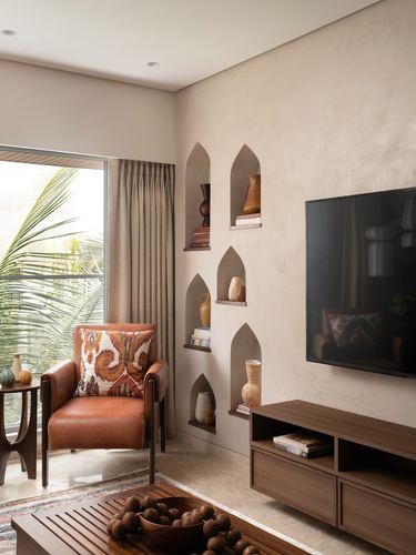 Living room corner with arched wall niches, leather armchair, and floating wood tv console