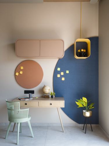 Kids study nook with circular pinboards, pink cabinet, and mint chair against beige wall