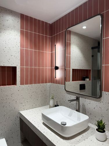 Bathroom with terracotta vertical tile, terrazzo counter, rectangular mirror and vessel sink