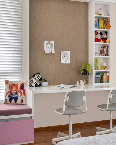 Children's study desk with built-in bookshelf, two grey task chairs, and a pink window seat below wooden blinds
