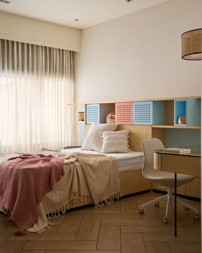 Child's bedroom with wood cubby headboard in blue and pink, layered throws on bed