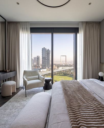 Neutral-toned bedroom with sheer curtains and floor-to-ceiling windows overlooking Dubai skyline