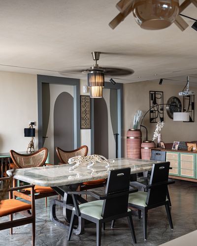 Dining room with marble table, mixed chair styles, ceiling fan light, and decorative leopard figurine