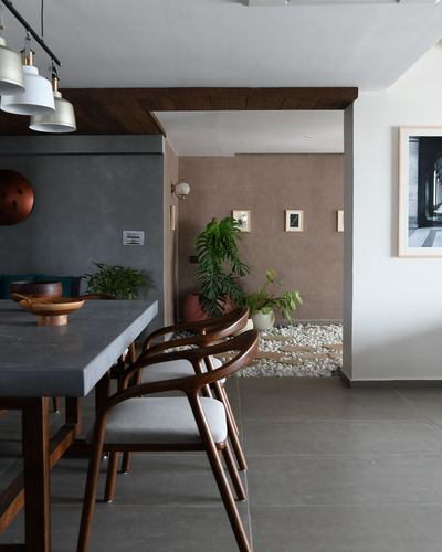Dining table with carved wooden chairs, view through arch to a pebble-floored courtyard with plants