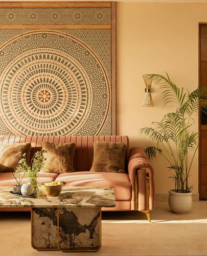 Living room with pink channel-tufted sofa beneath a large circular mandala mural and marble coffee table